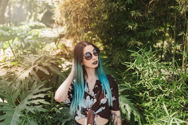 Portrait of a young woman wearing sunglasses standing in front of growing plant