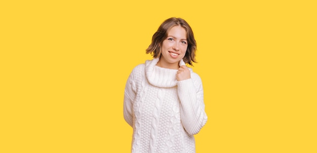 Portrait of a young woman wearing white sweater and smiling at the camera.