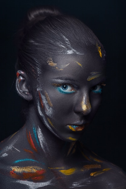 Portrait of a young woman who is posing covered with  black paint