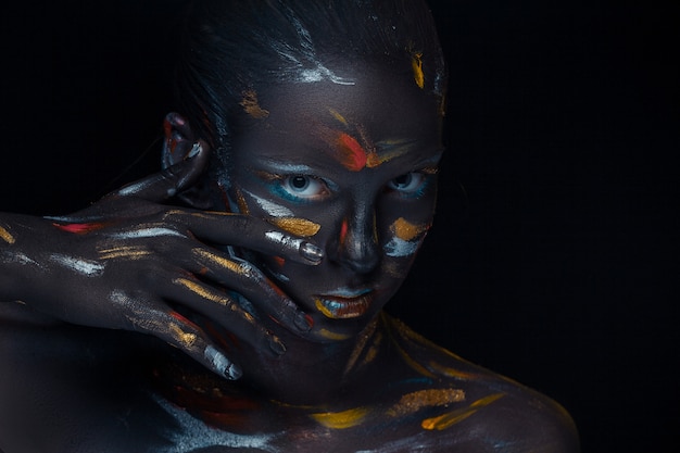 Portrait of a young woman who is posing covered with  black paint