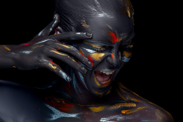 Portrait of a young woman who is posing covered with  black paint