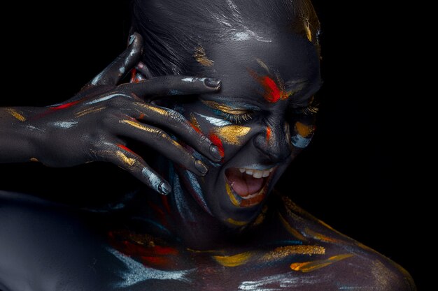 Portrait of a young woman who is posing covered with  black paint