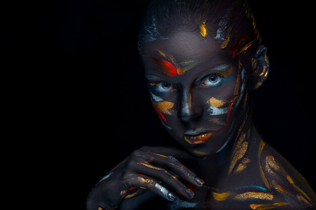 Portrait of a young woman who is posing covered with  black paint