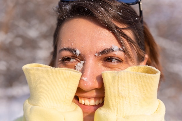 Portrait of a young woman in a winter forest on a sunny day with a snow-white smile, fooling around