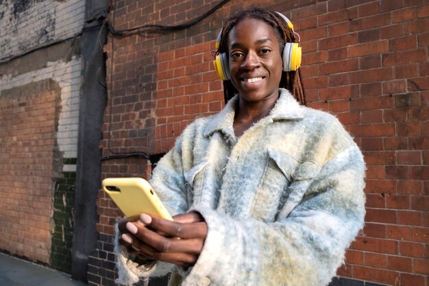 Portrait of young woman with afro dreadlocks listening to music on headphones
