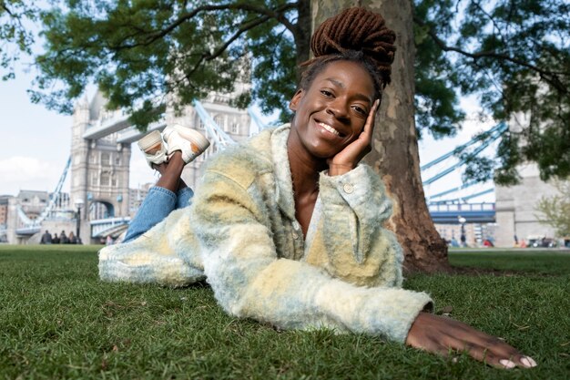 Portrait of young woman with afro dreadlocks posing on grass in the city