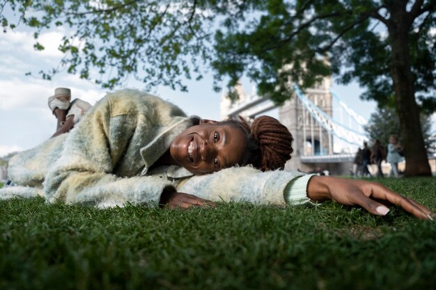 Ritratto di giovane donna con dreadlocks afro in posa sull'erba in città
