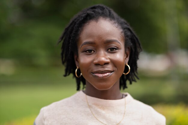 Portrait of young woman with afro dreadlocks posing outside