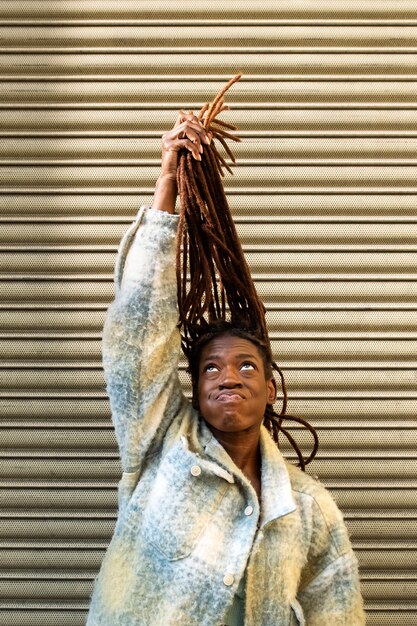 Портрет молодой женщины с афро-дредами, демонстрирующей свои волосы в городе