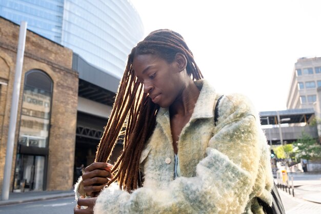 Portrait of young woman with afro dreadlocks showing off her hair while in the city