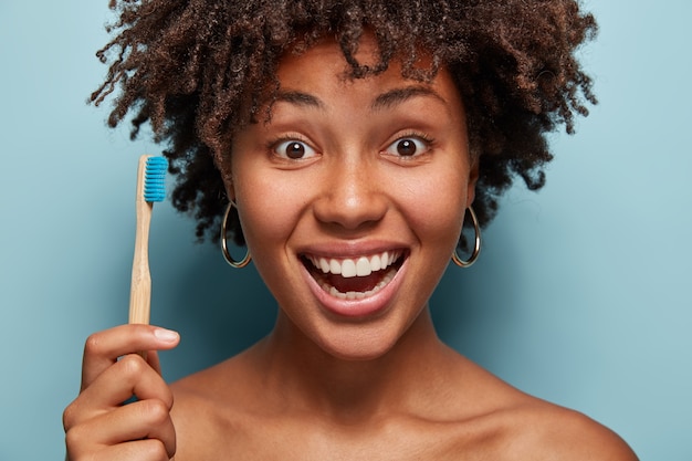 Ritratto di giovane donna con taglio di capelli afro tenendo uno spazzolino da denti