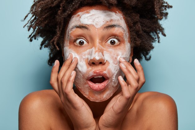 Portrait of young woman with Afro haircut washing her skin