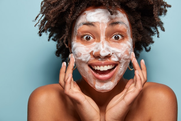 Portrait of young woman with Afro haircut washing her skin