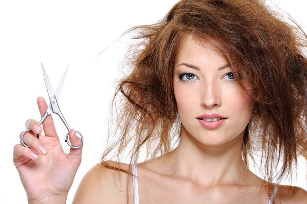 Portrait of young woman with backcombing hair and with scissors
