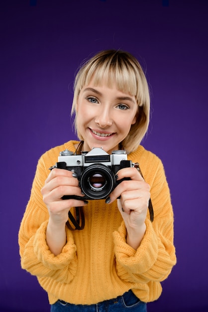 Foto gratuita ritratto di giovane donna con la macchina fotografica sopra la parete viola