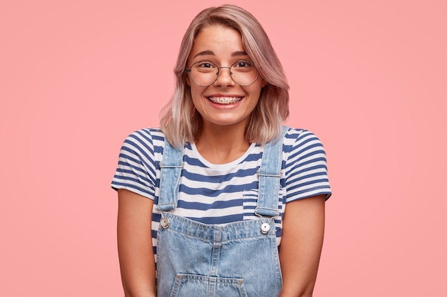 Free photo portrait of young woman with colored hair wearing overalls