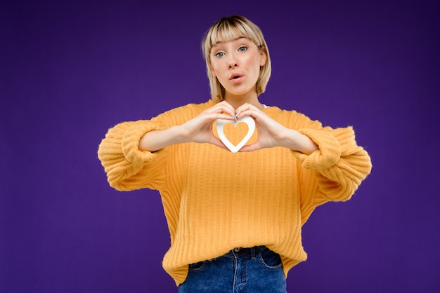 Portrait of young woman with decor heart over purple wall