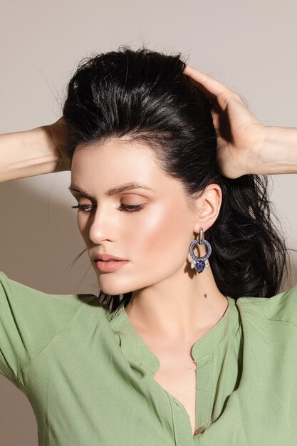 Portrait of young woman with earrings with a lot of blue gems isolated