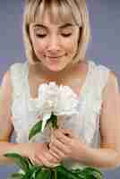 Foto gratuita ritratto di giovane donna con fiore sul muro grigio