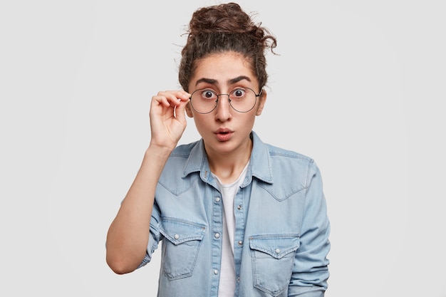 Portrait of young woman with hair in a bun and wearing denim shirt