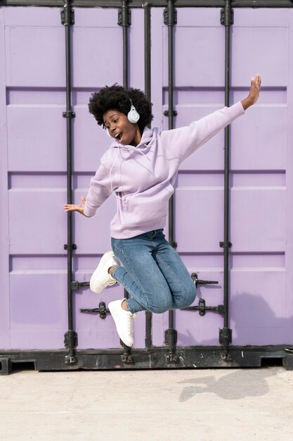 Portrait young woman with headphones jumping