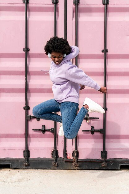 Portrait young woman with headphones jumping