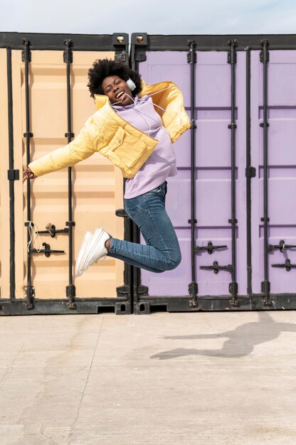 Portrait young woman with headphones jumping