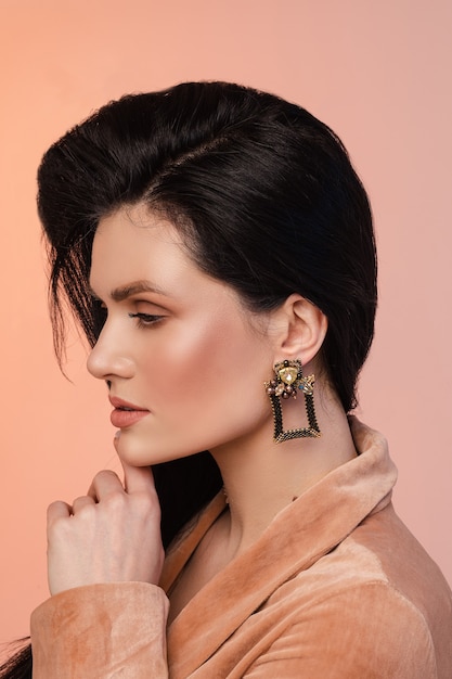 Portrait of young woman with healthy skin and black square earrings isolated on pink wall