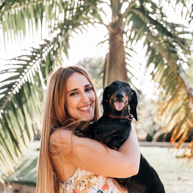 Foto gratuita ritratto di una giovane donna con il suo cane guardando la fotocamera