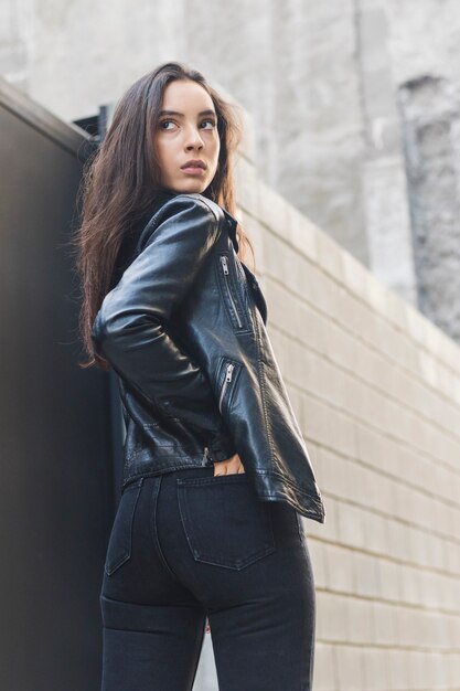 Portrait of a young woman with her hands in jeans pocket looking over the shoulder