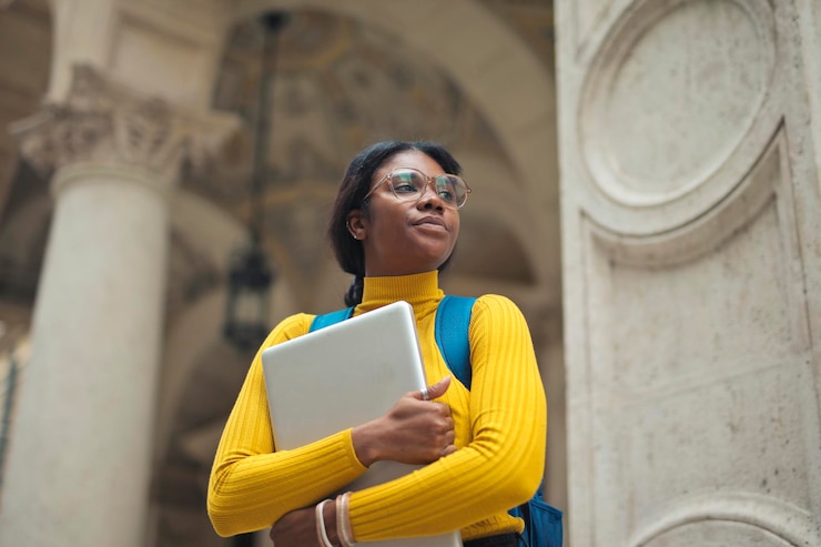 Free Photo portrait of young woman with laptop in hands outside a school