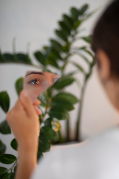 Free photo portrait of young woman with low self-esteem looking in a hand-held mirror