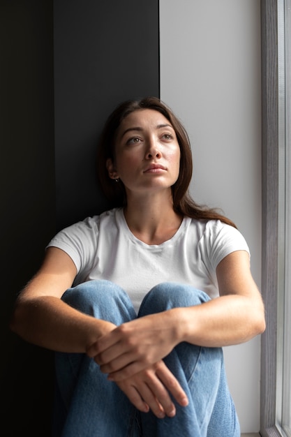 Free photo portrait of young woman with low self-esteem sitting in room at home