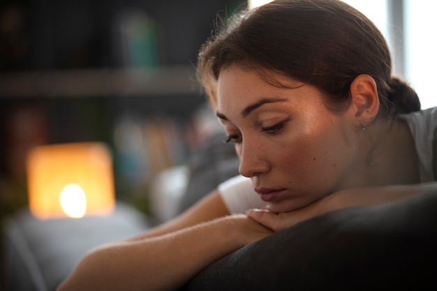 Free photo portrait of young woman with low self-esteem sitting on sofa at home