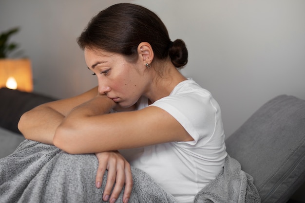 Free photo portrait of young woman with low self-esteem sitting on sofa at home