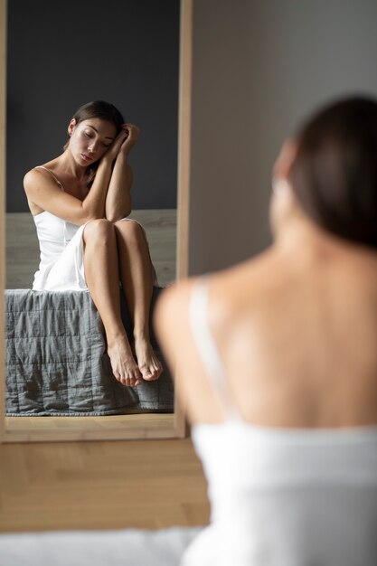 Portrait of young woman with low self-esteem with mirror