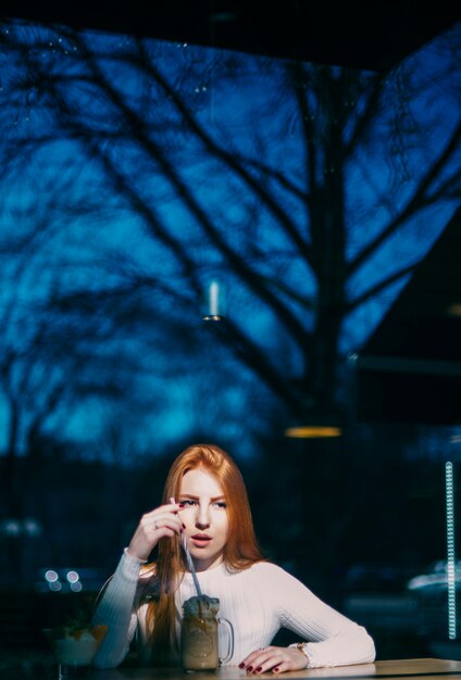 Portrait of a young woman with smoothie jar in caf�