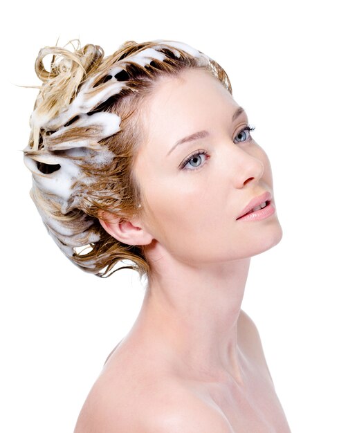 Portrait of young woman with soaping head with shampoo - white background