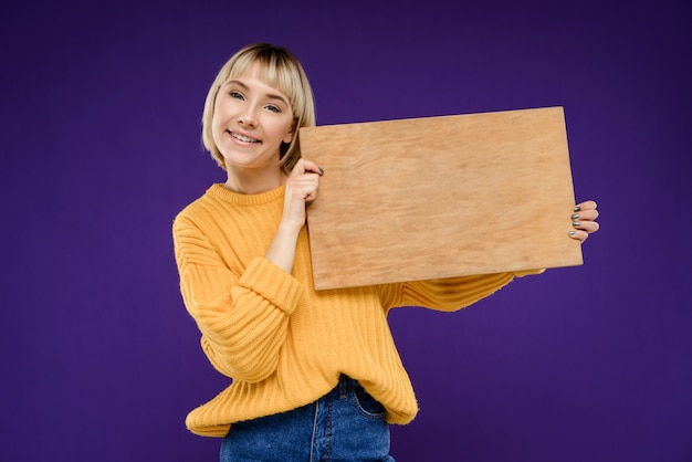 Free photo portrait of young woman with wooden desk over purple wall