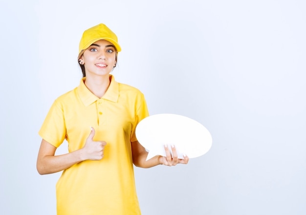 Портрет молодой женщины в желтой форме с пустым пустым речевым пузырем, показывающим большой палец вверх.