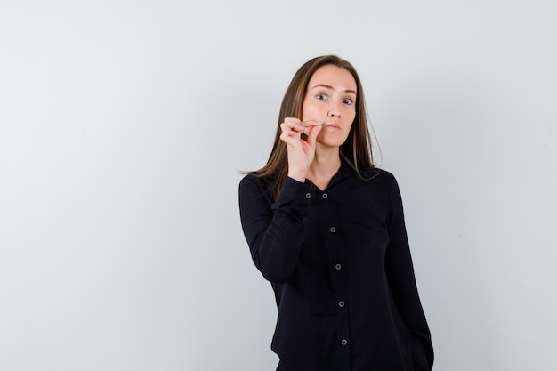 Free photo portrait of young woman zip gesture