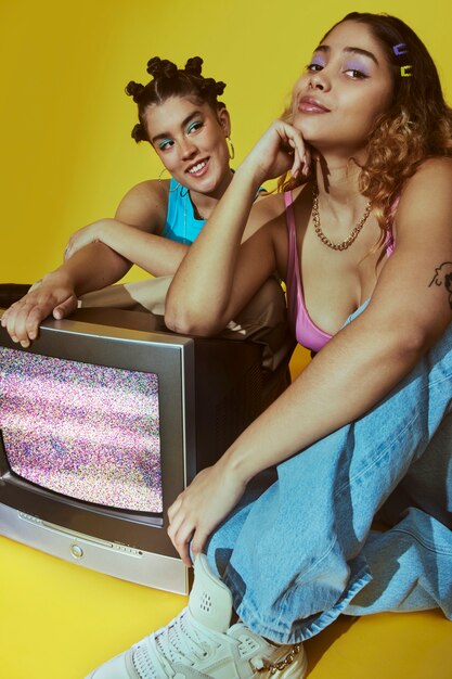 Portrait of young women in 2000s fashion style posing with tv