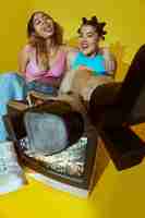 Free photo portrait of young women in 2000s fashion style posing with tv