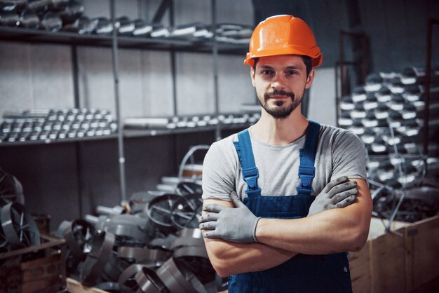 Портрет молодого рабочего в каске на большом металлообрабатывающем заводе.