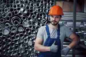 Foto gratuita ritratto di un giovane operaio in un cappello duro in un grande impianto di lavorazione dei metalli.