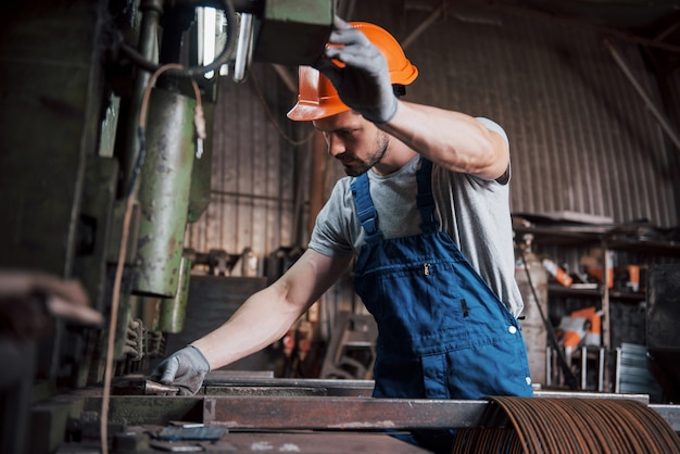 大規模な金属加工工場でヘルメットをかぶった若い労働者の肖像画。