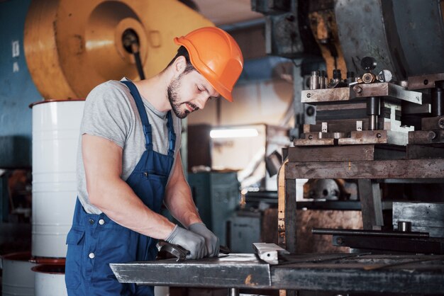 Portrait of a young worker in a hard hat at a large waste recycling factory.