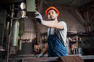 Free photo portrait of a young worker in a hard hat at a large waste recycling factory.