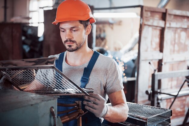 Portrait of a young worker in a hard hat at a large waste recycling factory.