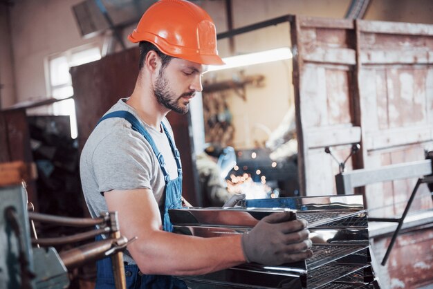 portrait of a young worker in a hard hat at a large waste recycling factory